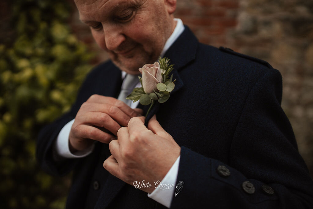 Groom adjusting his floral button-hole prior to wedding at Orrocco Pier. 