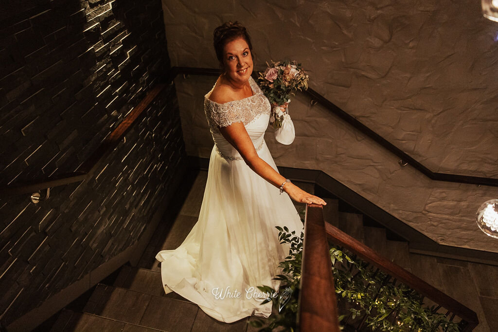 Scottish bride standing on staircase at Orrocco Pier holding wedding bouquet