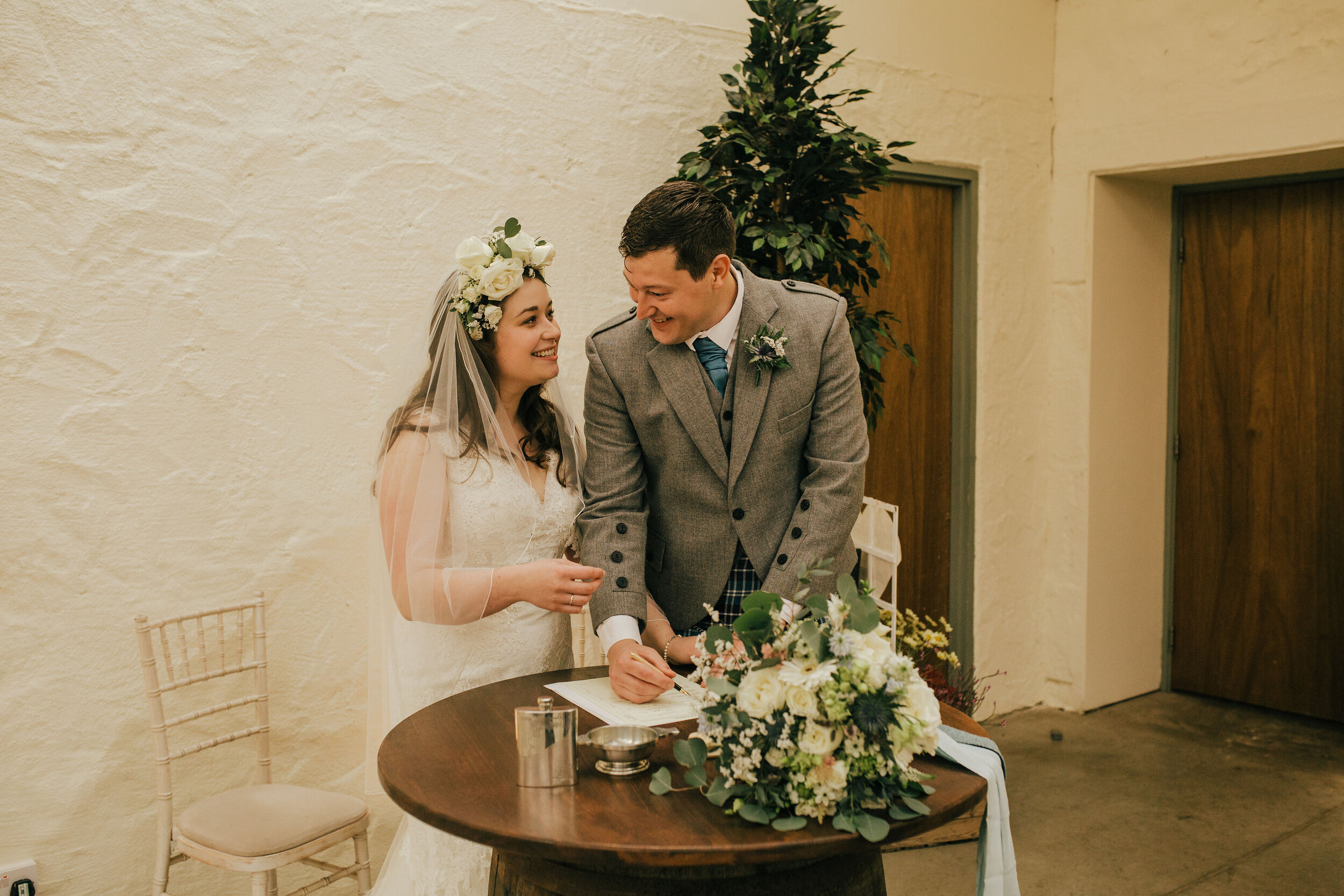 Bride and Groom getting married at Bachilton Barn, Scotland with Wedding flowers on table.