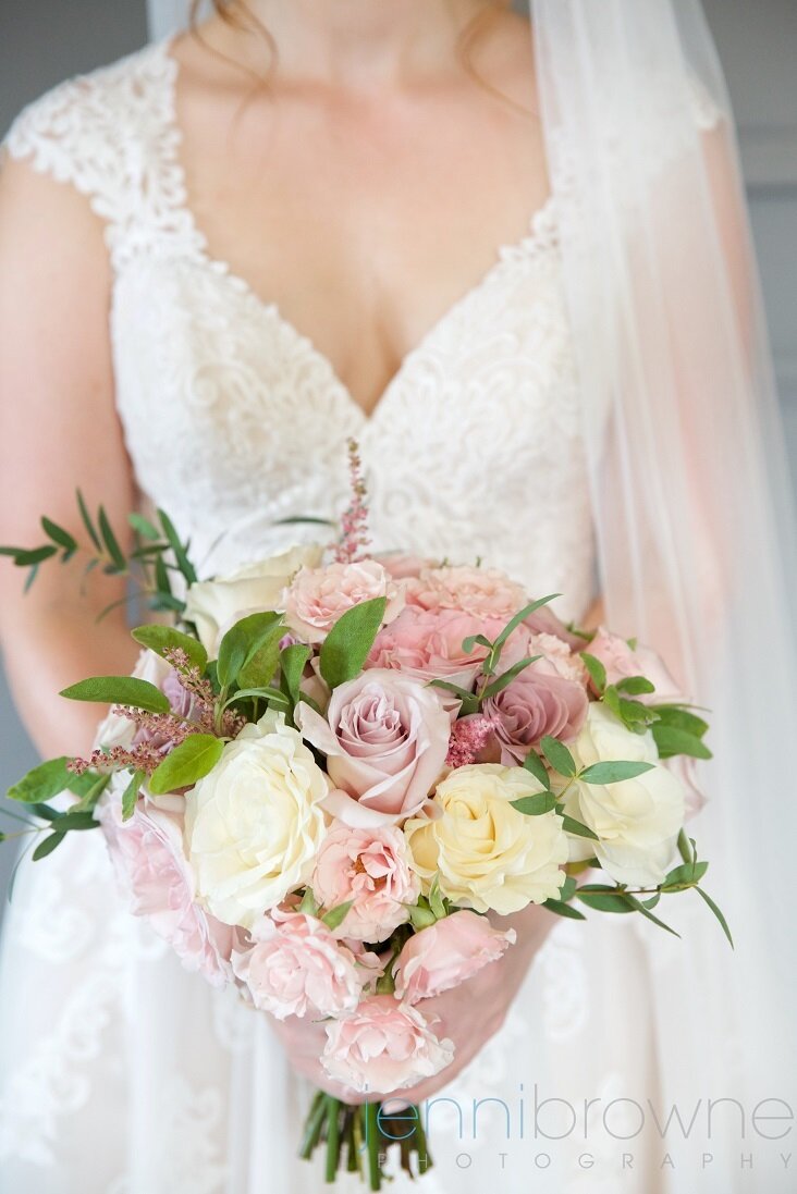 Scottish bride holding her beautiful wedding bouquet which includes green foliage, cream and dusky pink roses. Photo by Jenni Browne Photography. 