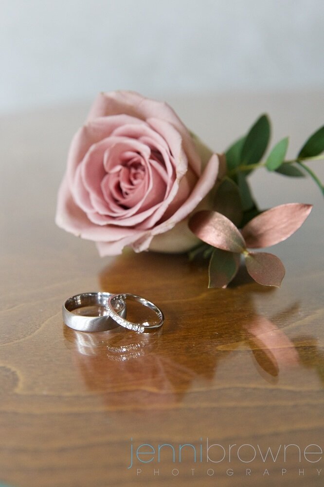 Dusky pink rose corsage pictured with wedding rings. 
