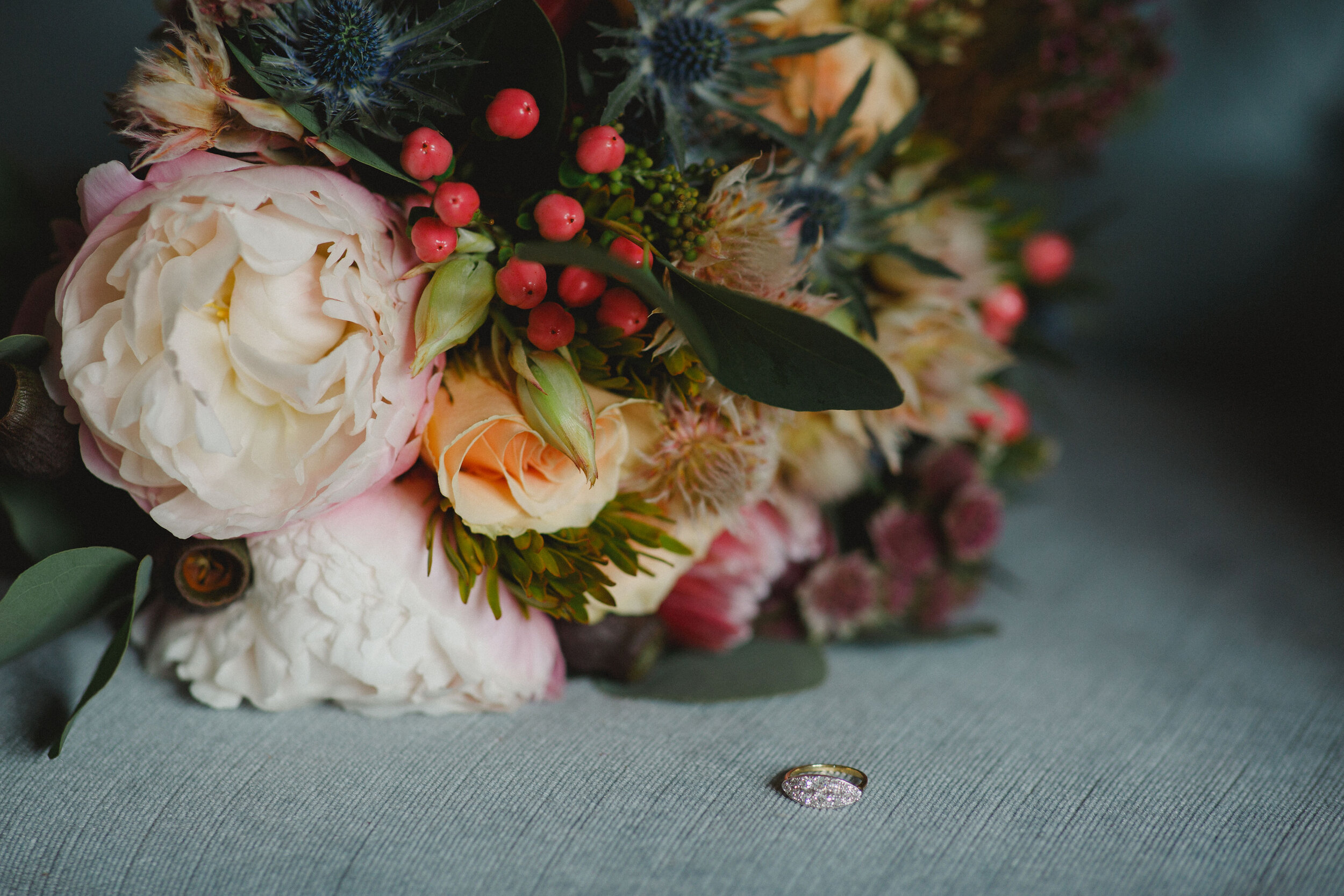 Romantic wedding bouquet containing blush pink peonies and pink berries. 