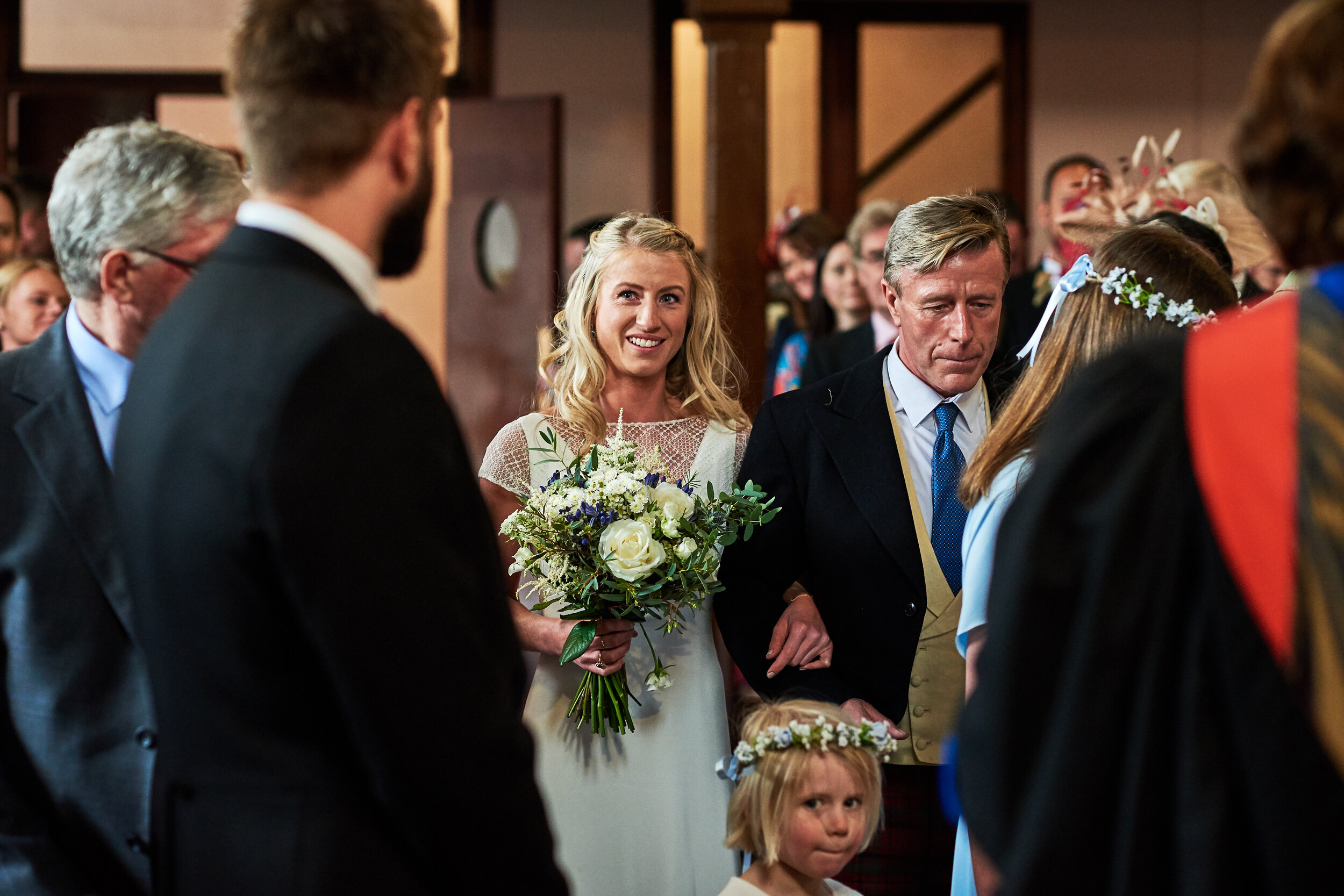 Bride walking down the Aisle holding green and cream wedding bouquet.