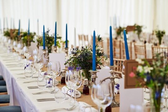 Wedding tables with white table clothes, green foliage and blue candles at Scottish Wedding 