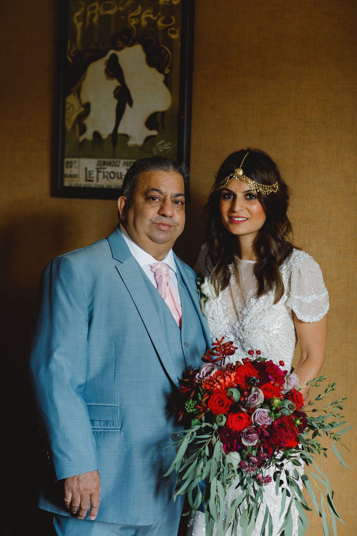 Bride wearing beaded gown and gold headdress standing next to father holding bridal flowers at Carphin house, St Andrews