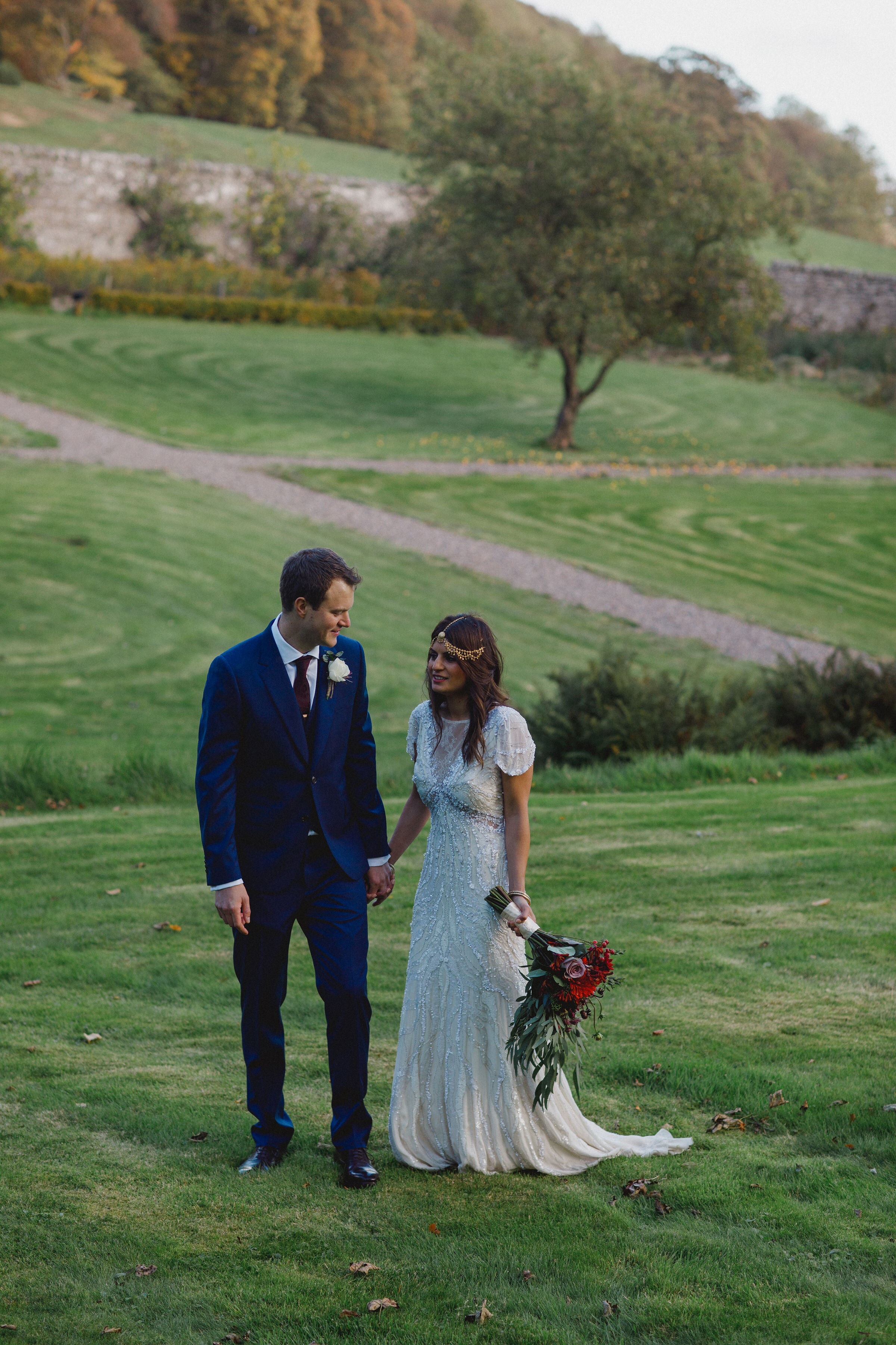 Bride and Groom standing in grounds of Carphin House, St Andrews with wedding flowers