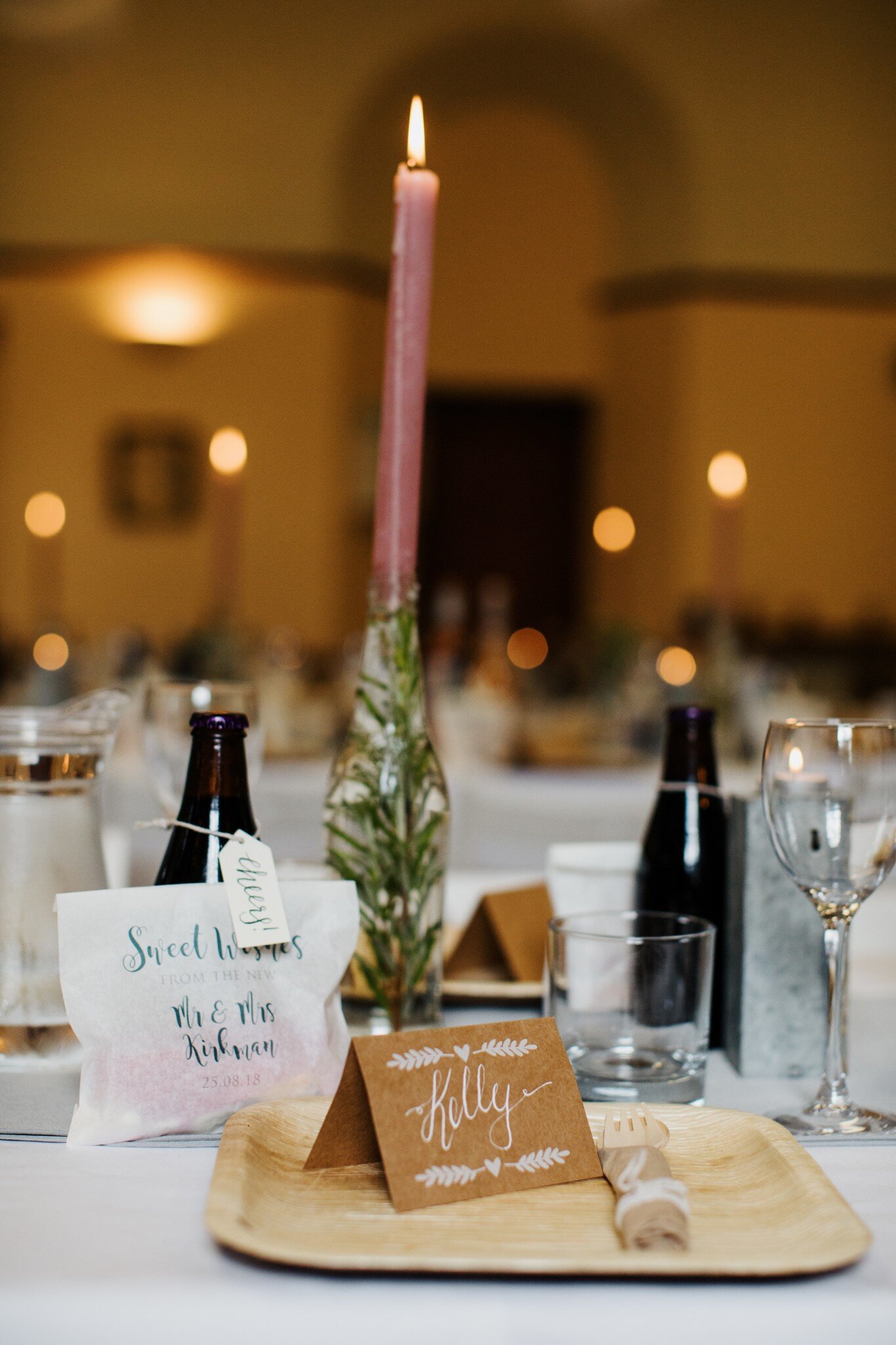 Glass bottle with Eucalyptus and pink candle and table setting at Scottish wedding