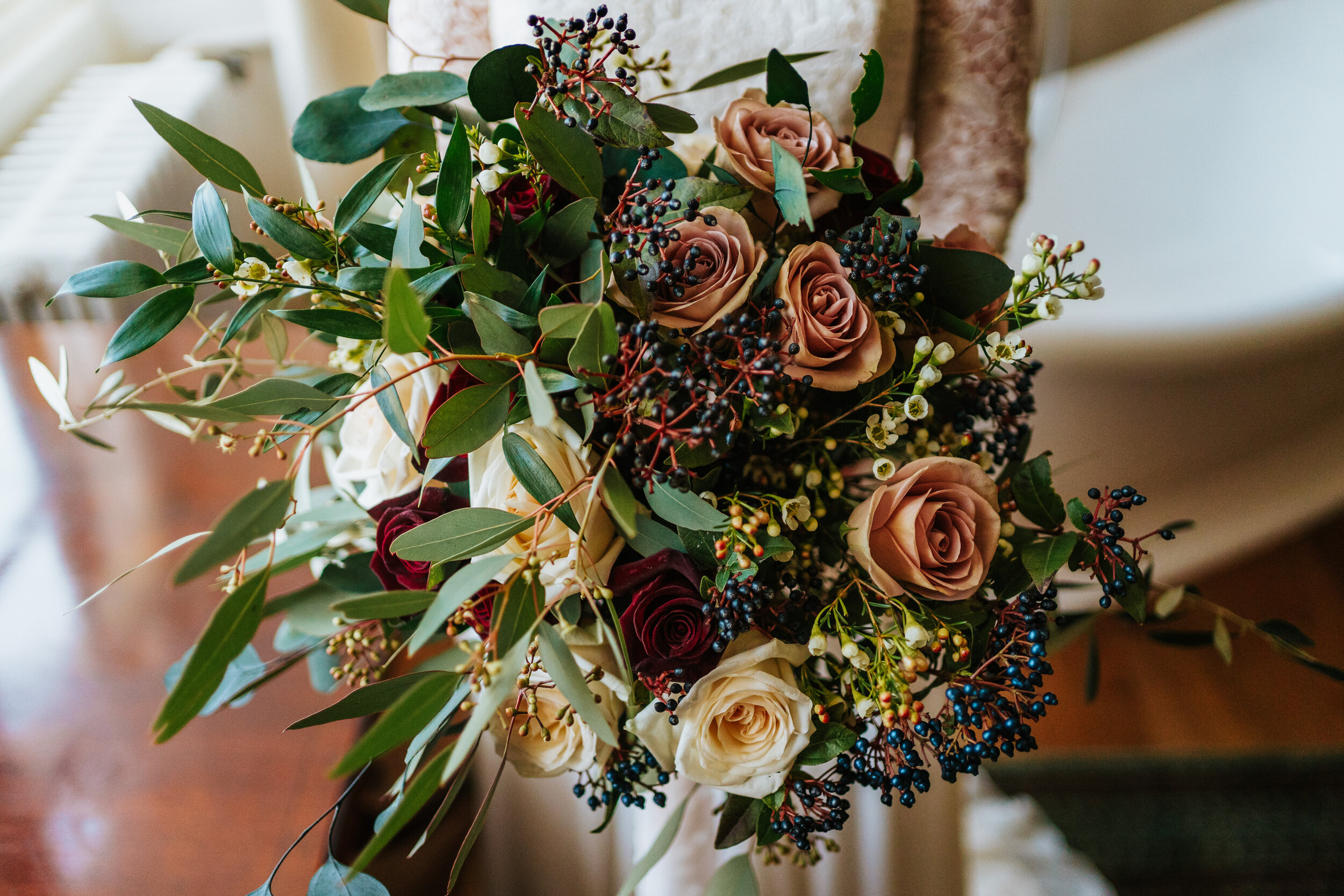 Hand tied bridal bouquet of roses and berries with green foliage