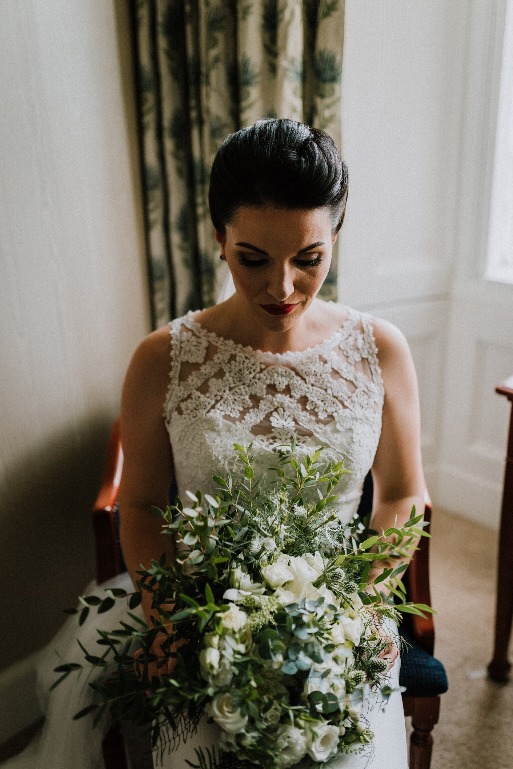 Scottish bride in lace gown holding hand tied wedding flowers at Bachilton Barn 