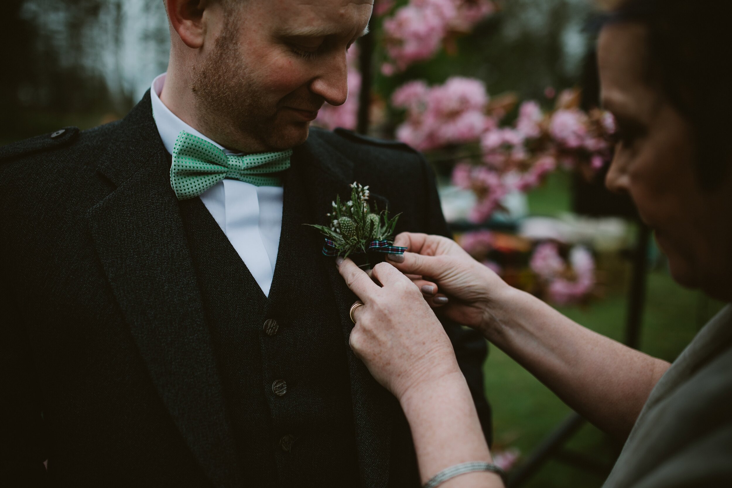 Buttonhole being pinned on groomsman at Scottish wedding 