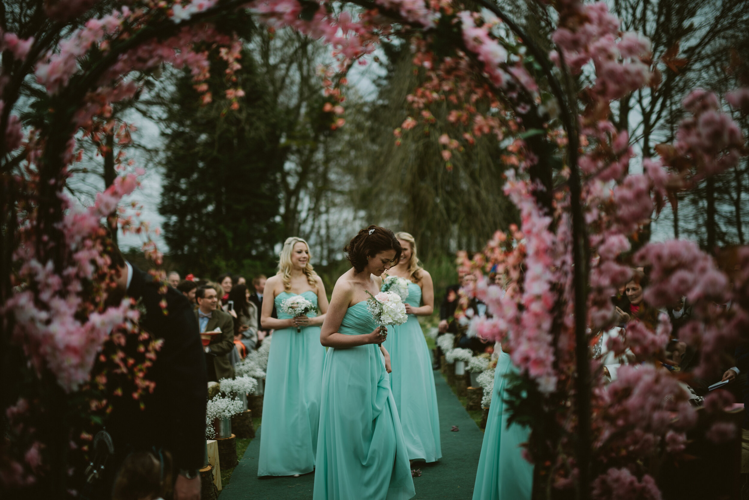 Bridesmaids walking down the aisle to a floral arch at Scottish wedding 