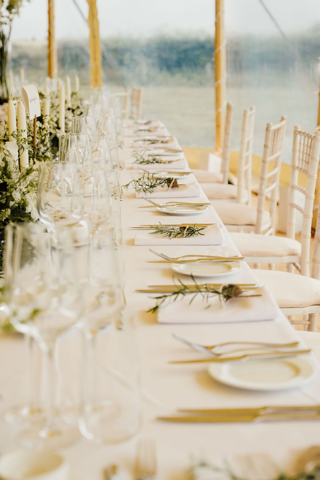 Tablescape at summer wedding featuring white candles and green foliage