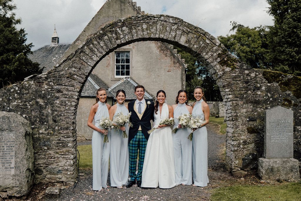 Groom standing with Bride and her bridesmaids outside scottish wedding venue