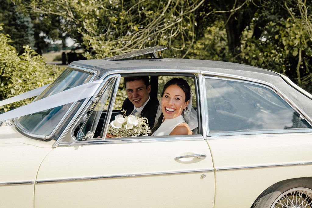 Bride and Groom portrait in vintage car at summer wedding