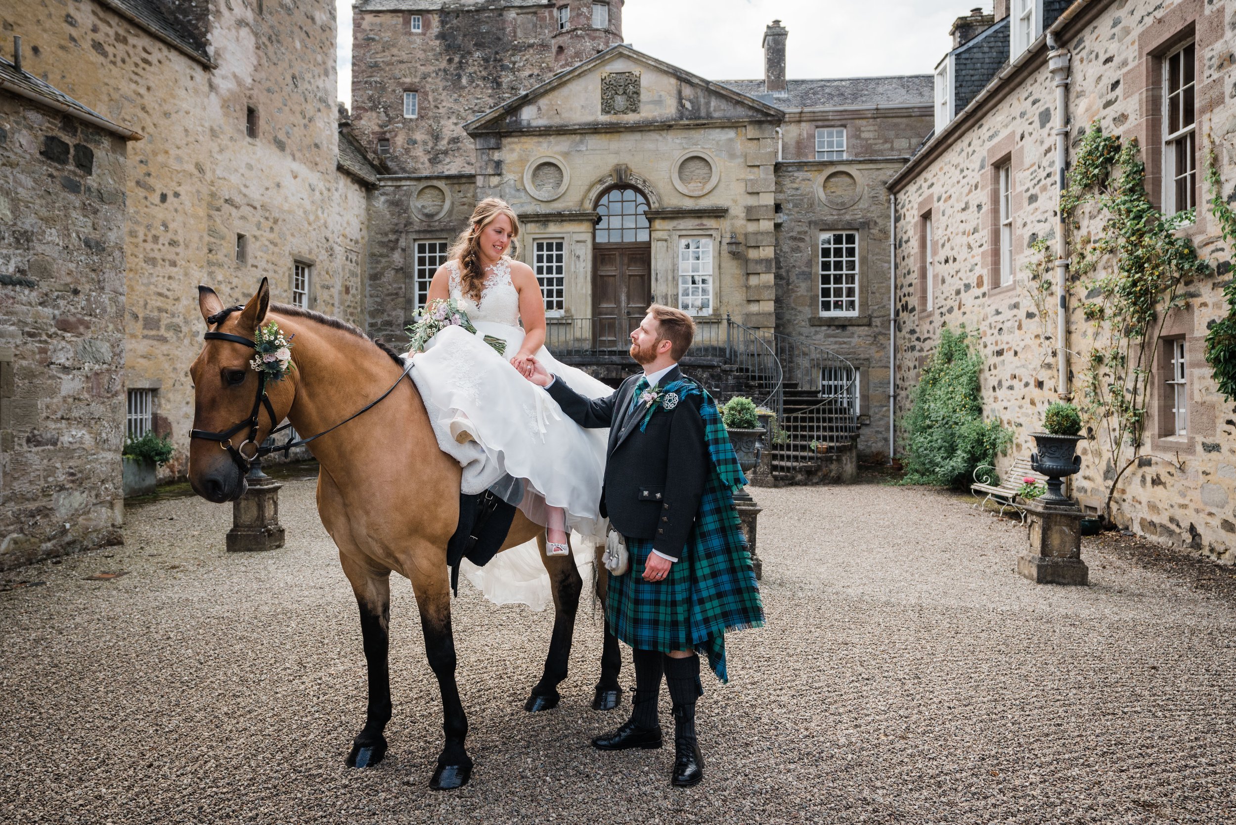 Bride on horseback next to groom outside Cardney Steady, Dunkeld