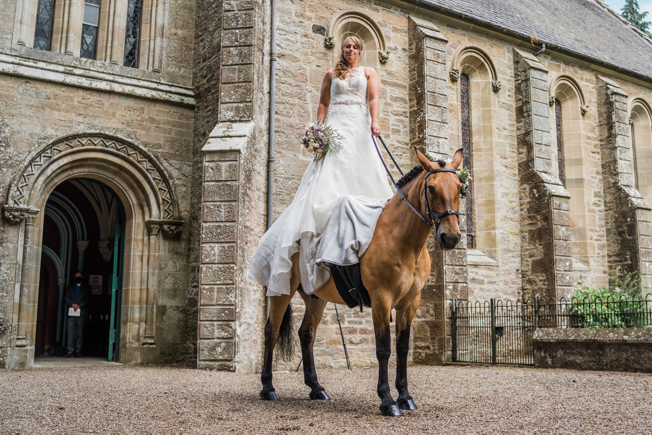 Bride standing on horseback outside Scottish country church