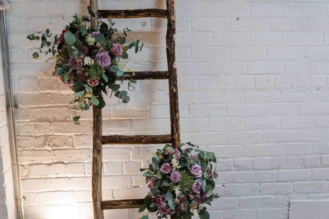 Rustic ladder decorated with lilac flowers and greenery