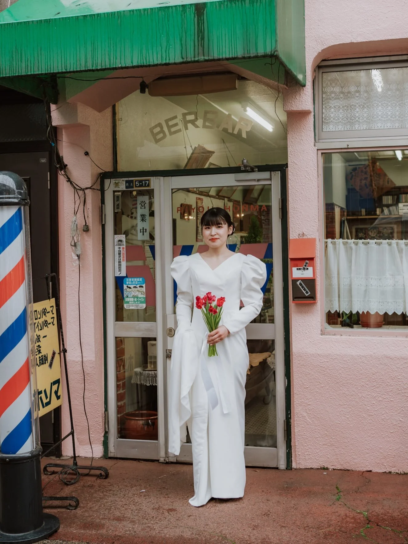 盛岡・桜山で、結婚の写真。

この日は、雨。
新婦が雨に濡れない場所を探していると、床屋さんの屋根の下が乾いていた。

このお店、実は数十年前に自分が子どもの頃、母に連れられて髪を切ってもらっていた場所。 店の中には大きな金魚のいる水槽があって、それを見るのが楽しみだった。
急に、子どもの頃の記憶がよみがえる。
大人になって、この場所で誰かの結婚の写真を撮るなんて、想像もしなかった。
「ここで撮らせてもらえませんか」
そう声をかけると、女将さんはこころよく迎えてくれた。
後日、お礼のお団子を持っ