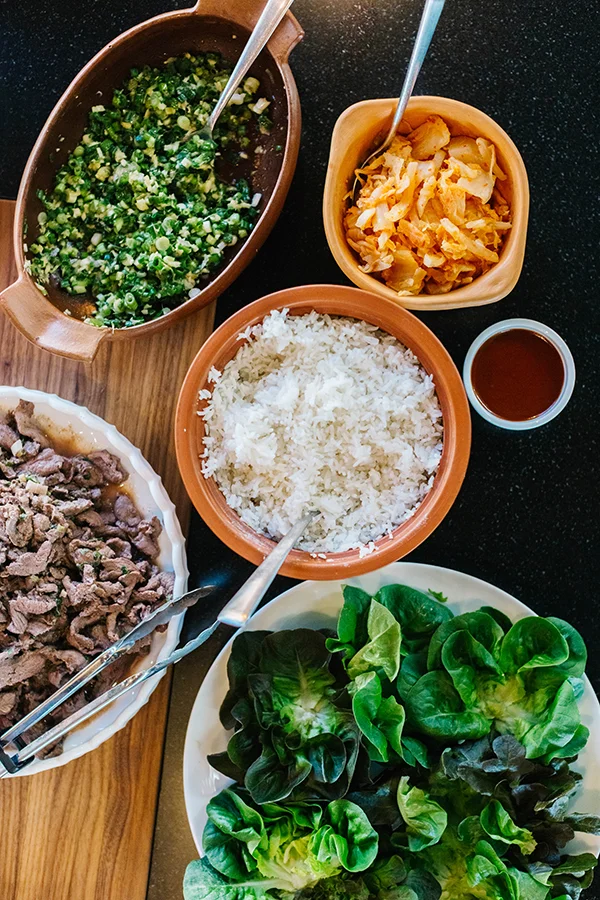 Clockwise from top left: scallion-ginger salsa, kimchi, ssam sauce, steamed rice, winter lettuce, locally sourced elk. 