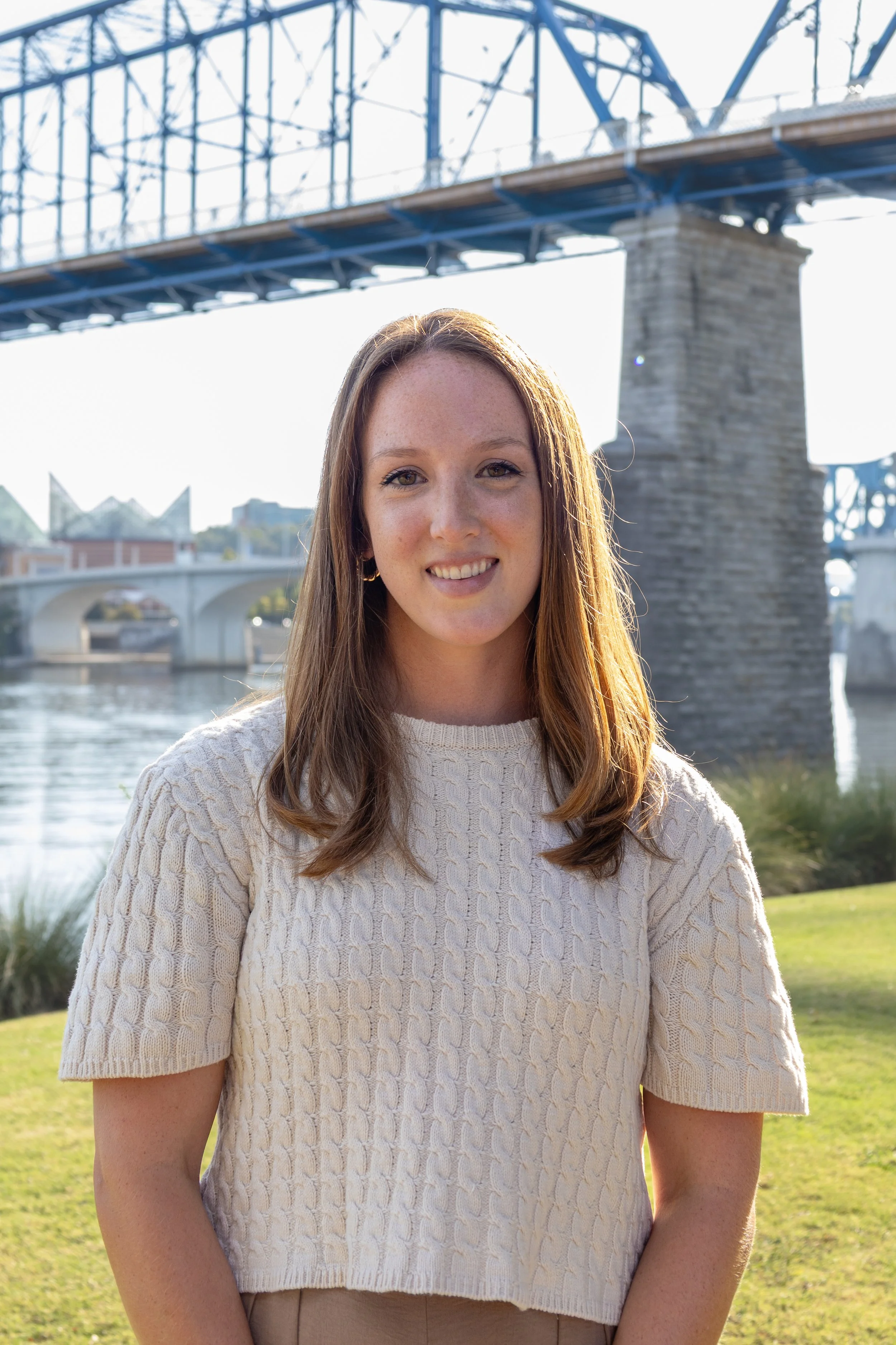 Girl in cream colored shirt beneath a bridge and river in Chattanooga TN.