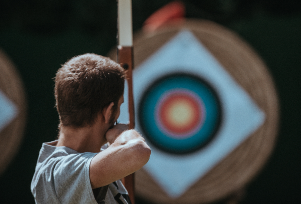 Image of a person with a bow and arrow looking at an archery target