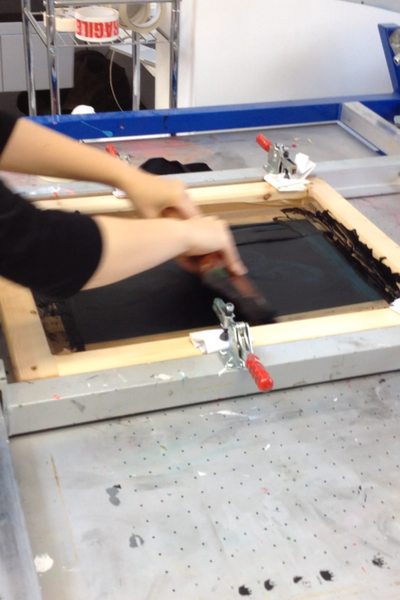 Using a squeegee when screen-printing to push the ink through the stencil