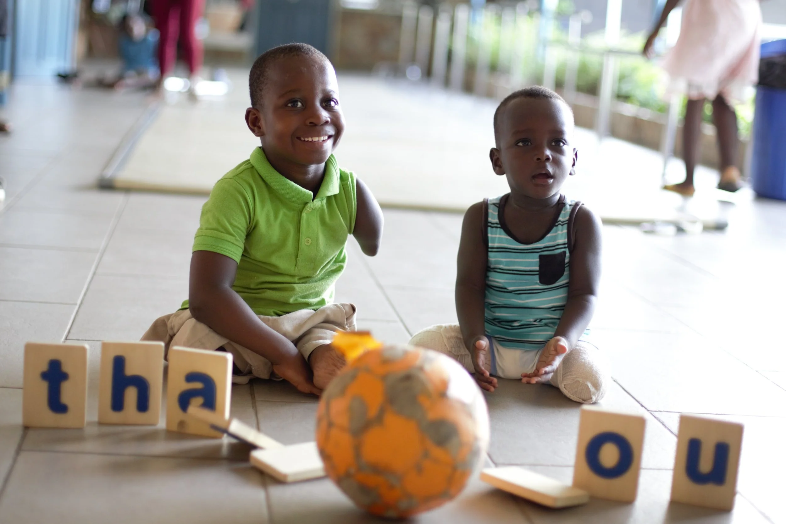 Blessing and Kobe, Two Children in the Care of the Orthopedic Training Center in Ghana, West Africa, Express Their Gratitude For Project Lolo's Support with Tumbling Block Letters. Credit: Orthopedic Training Center (OTC)