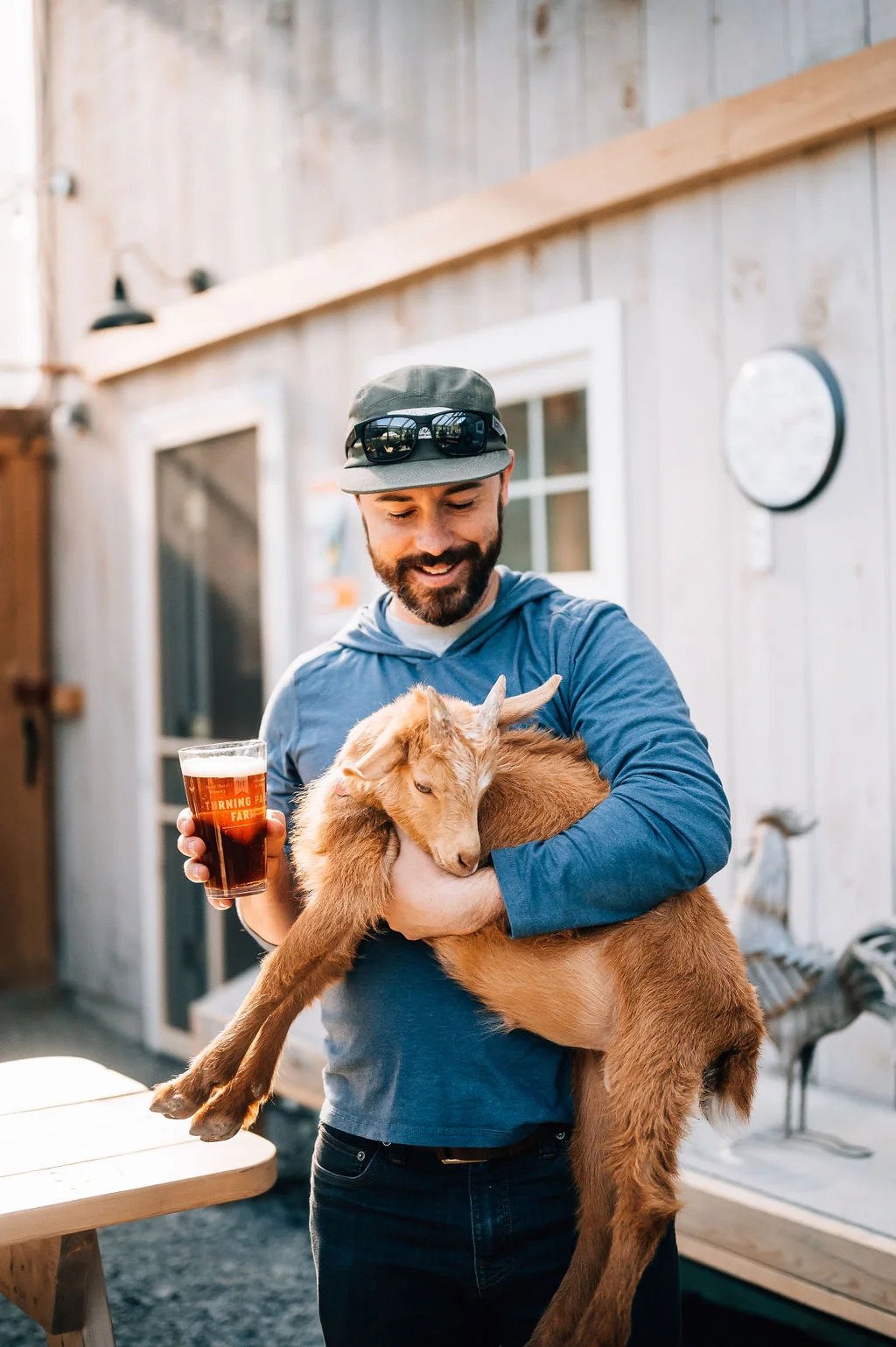 guy-with-beer-at-brewery-holding-goat-monson-maine-04464-turning-page-farm.jpg