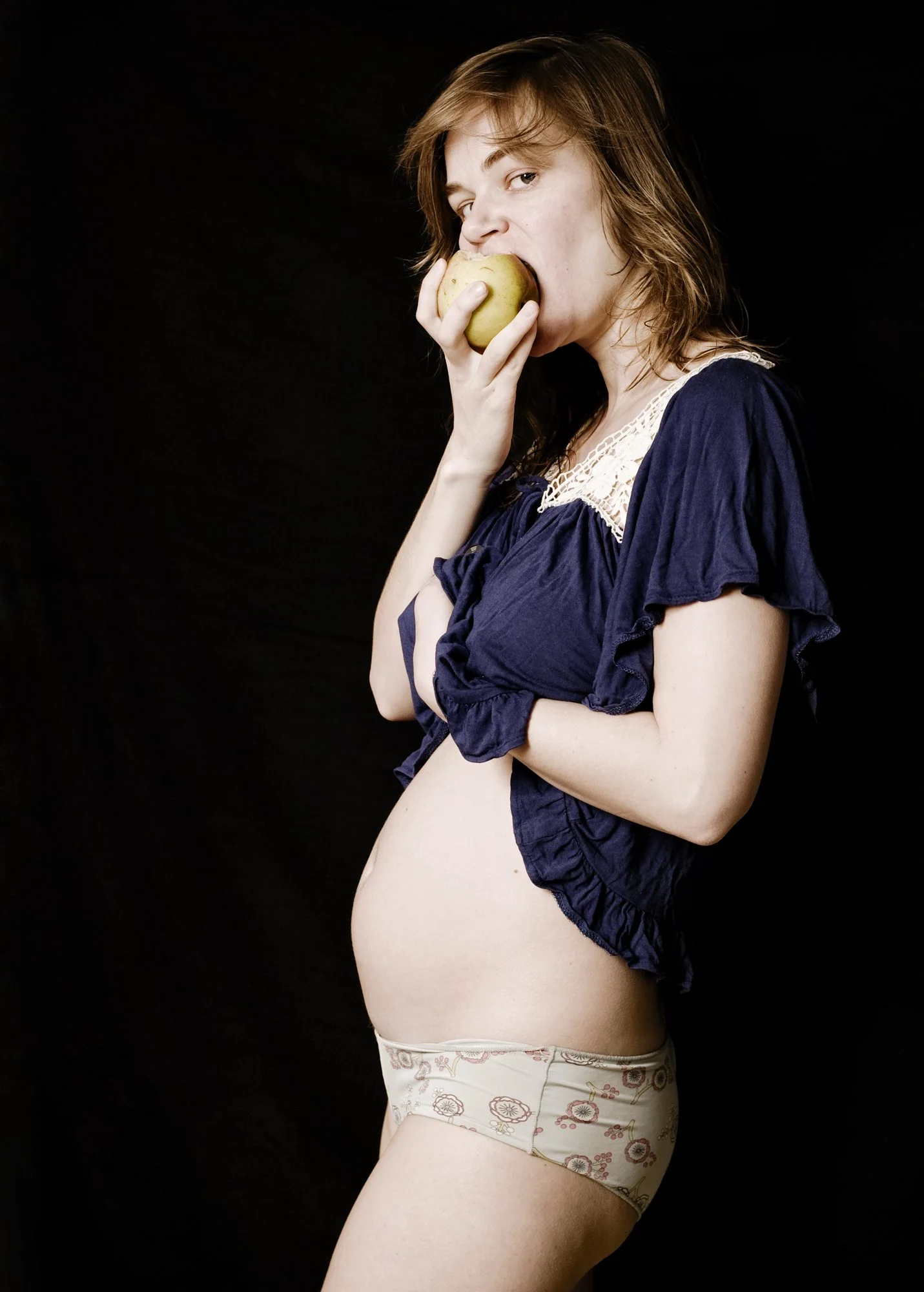 A pregnant woman eating an apple