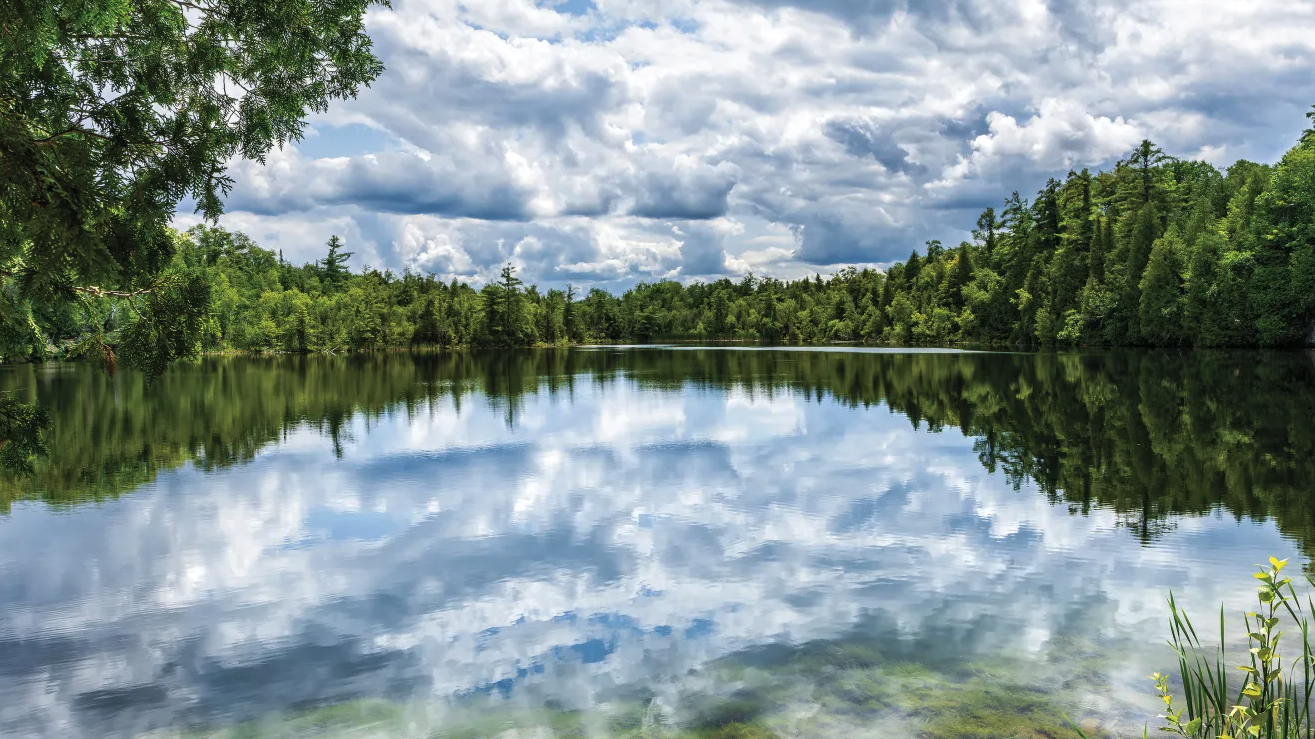 A picture of Crawford Lake where the clouds in the sky are reflected on the lake's surface.
