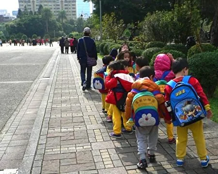 小朋友們遊玩結束後,撿起地上的書包,列隊離開。(曾錚 攝影)