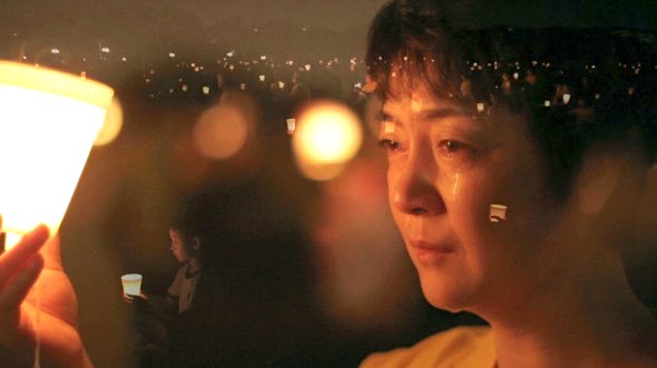 Jennifer Zeng sits at a candlelight vigil held for persecuted and killed Falun Gong practitioners in China. Zeng’s story is told in “Free China: The Freedom to Believe,” which will be in theaters in Los Angeles on May 31 and in New York on June 7. (Screenshot from “Free China” trailer)
