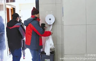 A Chinese man taking toilet paper from a public restroom in Beijing. 一名北京人正在卷走公廁中的手紙。