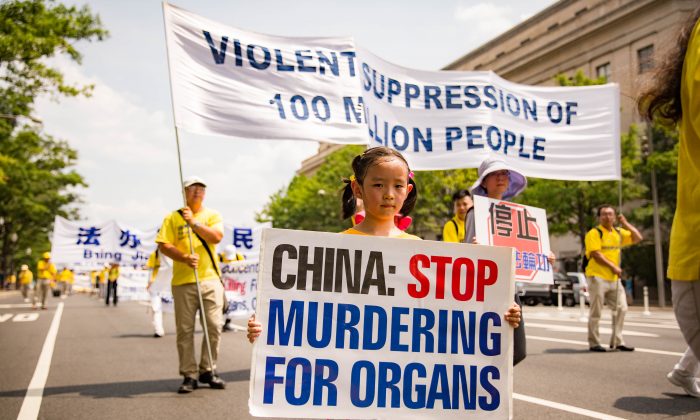A young Falun Dafa adherent holds a sign asking for China to stop killing prisoners of conscience for their organs in a parade in Washington on July 20, 2017. (Benjamin Chasteen/The Epoch Times)