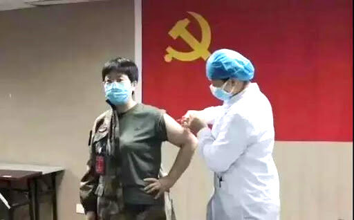 Chen Wei receiving an injection in front of the CCP flag. 