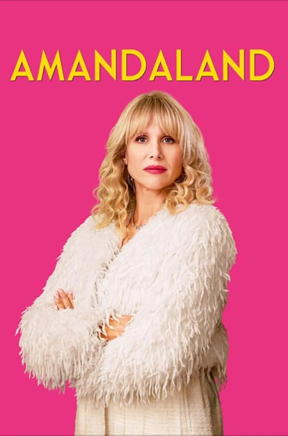 Cover of the TV show "Amandaland" featuring a woman with blonde curly hair, wearing a white fluffy coat, standing against a pink background.