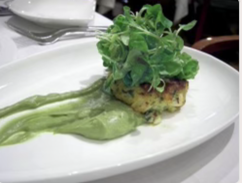 Arugula topped crab cake on lemon zested guacamole 