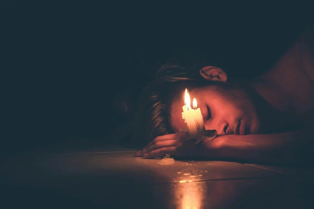 Man on the floor with candles representing men mental health challenges