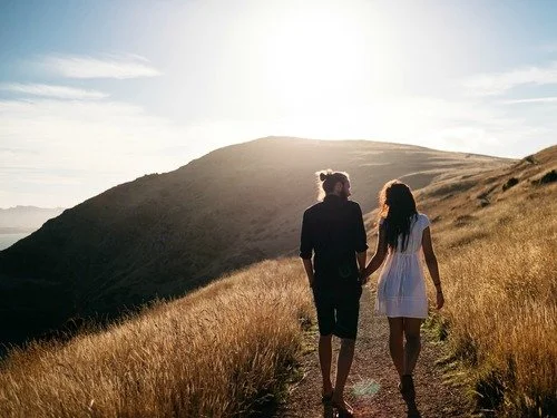 Young couple walking through a field representing the relationship journey