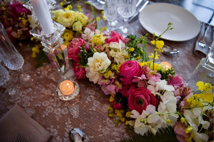 a summery floral garland, snakes across the guest tables, flowers include ranunculus, hydrangea, tulips, dancing lady orchids (oncidium) and fragrant geranium greens, created by Darwin florist, Beija Flor