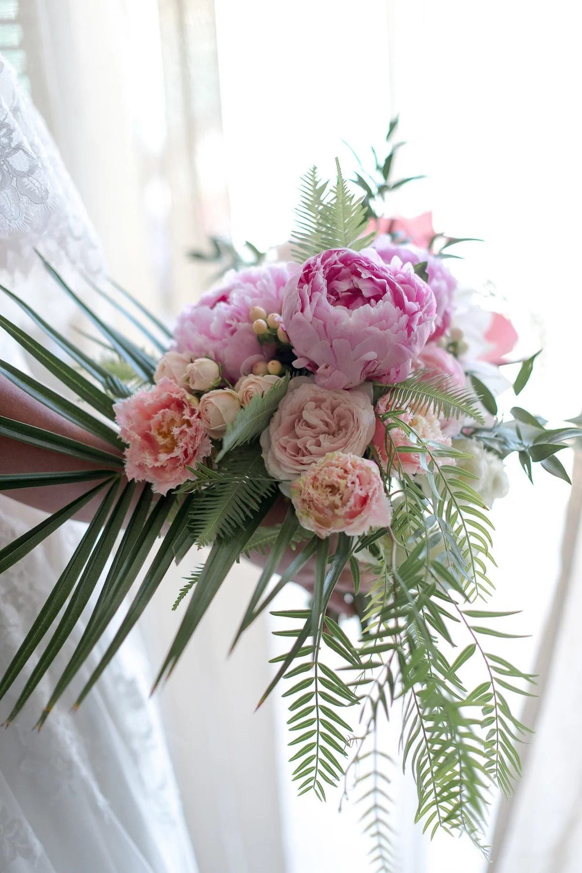 brides bouquet of Sarah Bernhardt peonies with frilled tulips and palms for a tropical feel.