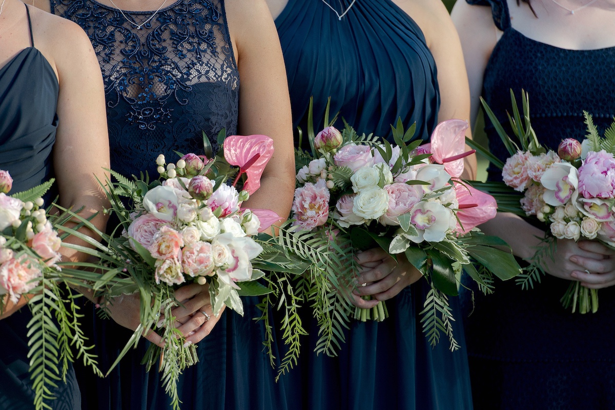 Bridesmaids in navy dresses with pink fresh flower bouquets