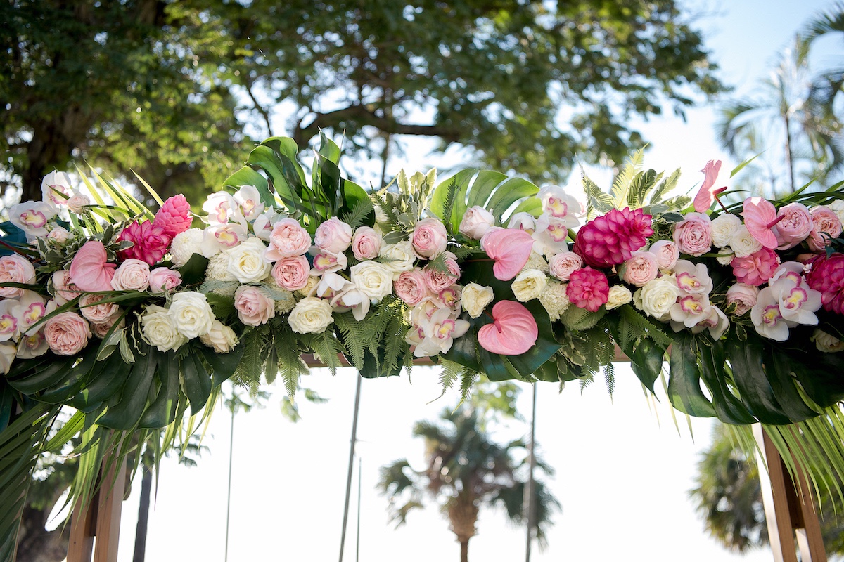 White roses, orchids, monstera leaves, fresh flowers for timber wedding arbour in Darwin.