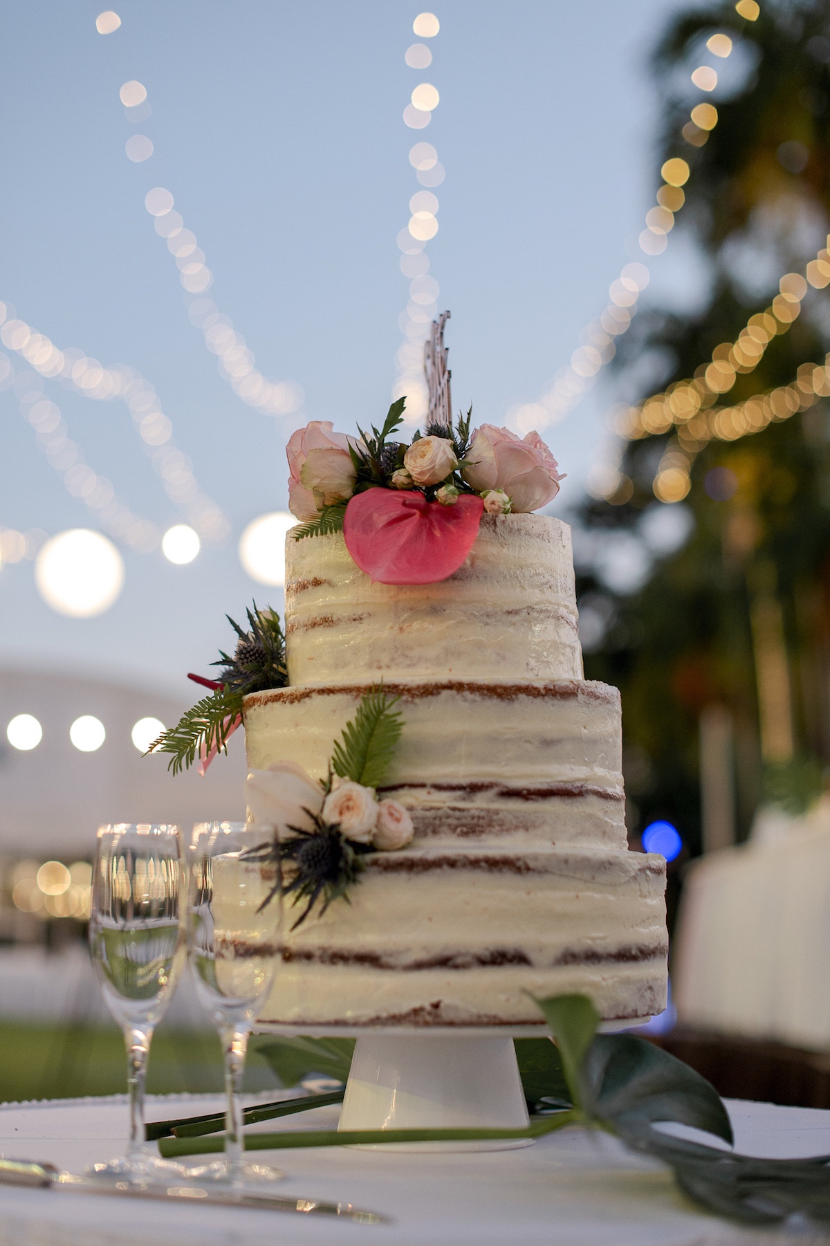 Three tier semi naked wedding cake dressed wth fresh flowers from Darwin florist, Beija Flor.