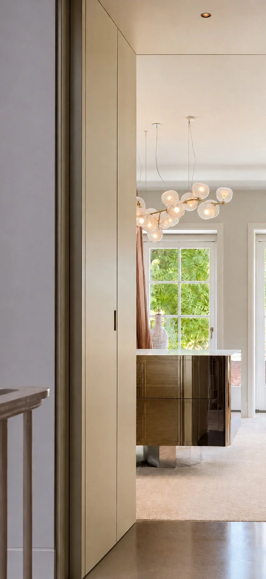 4. Dressing room threshold: A bespoke champagne portal framing the dressing room, featuring a mirror-polished stainless-steel island and a delicate Maehwa pendant by Giopato & Coombes.