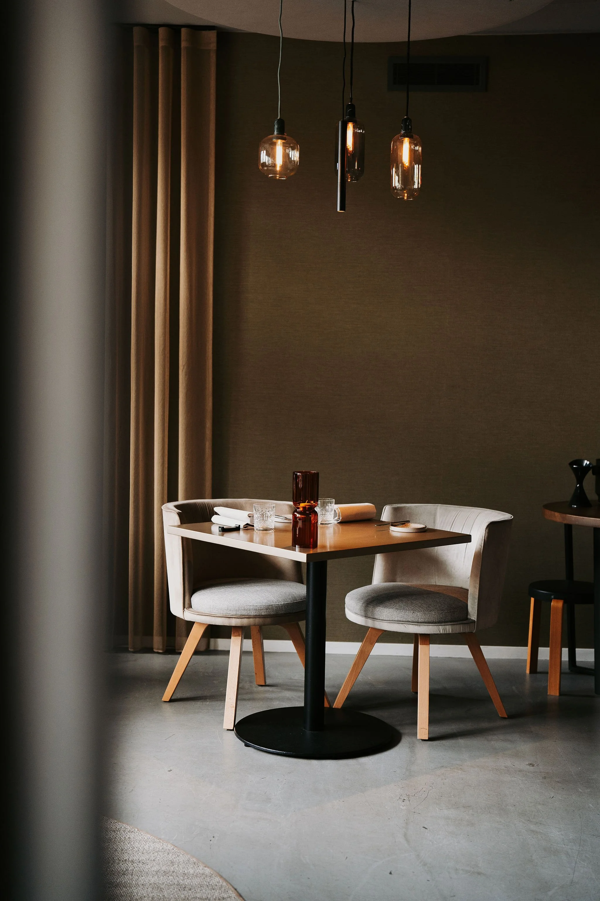 Dining detail: Minimalist table setting with two chairs, highlighting the balanced interior design of Restaurant Vermeer.