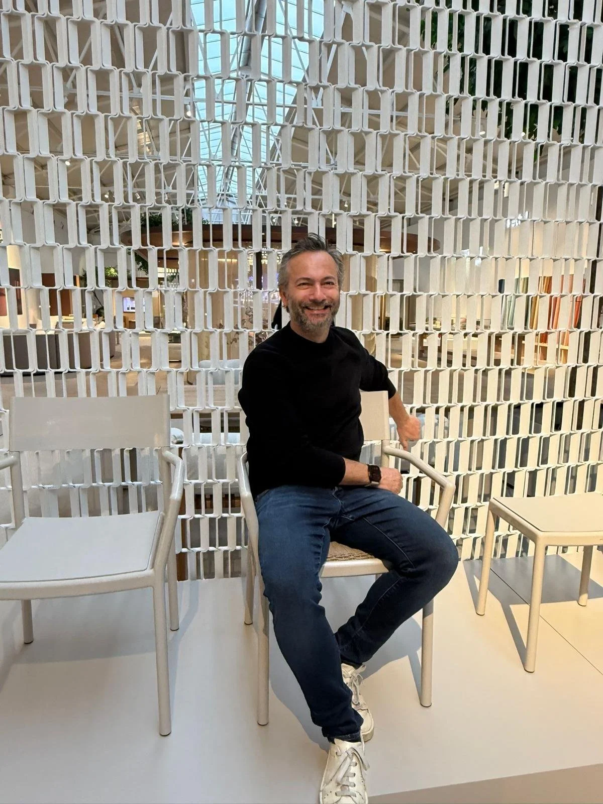   Designer portrait:  Designer Michiel Wijnen seated in front of the white Nazka Screen at the Kettal Salone del Mobile booth. 