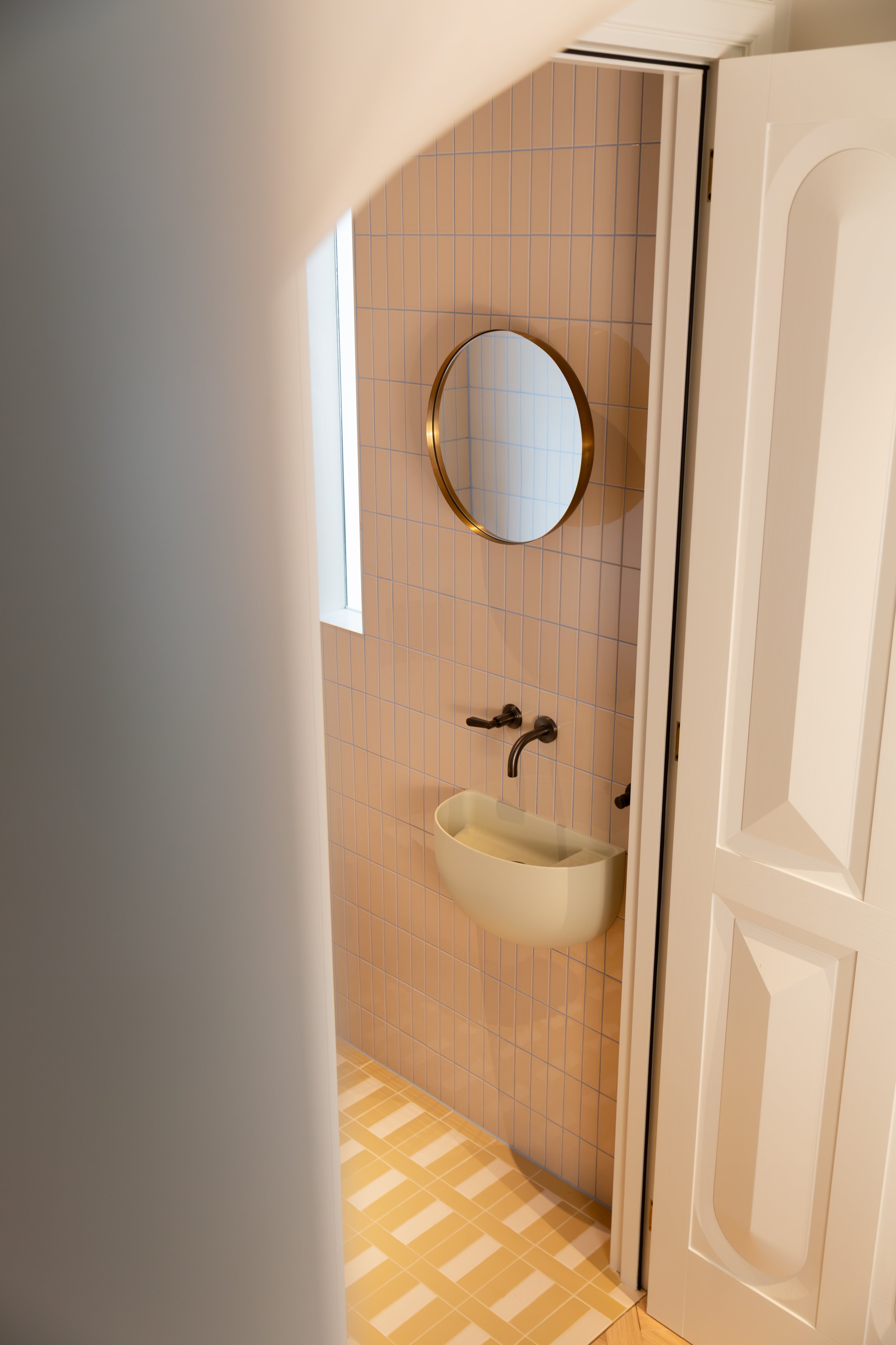 17. Minimalist monochromatic bathroom: Clean, monochromatic bathroom featuring a Falper Bowlino basin, understated Quintessenza Argblock tiles, and a custom-designed door.