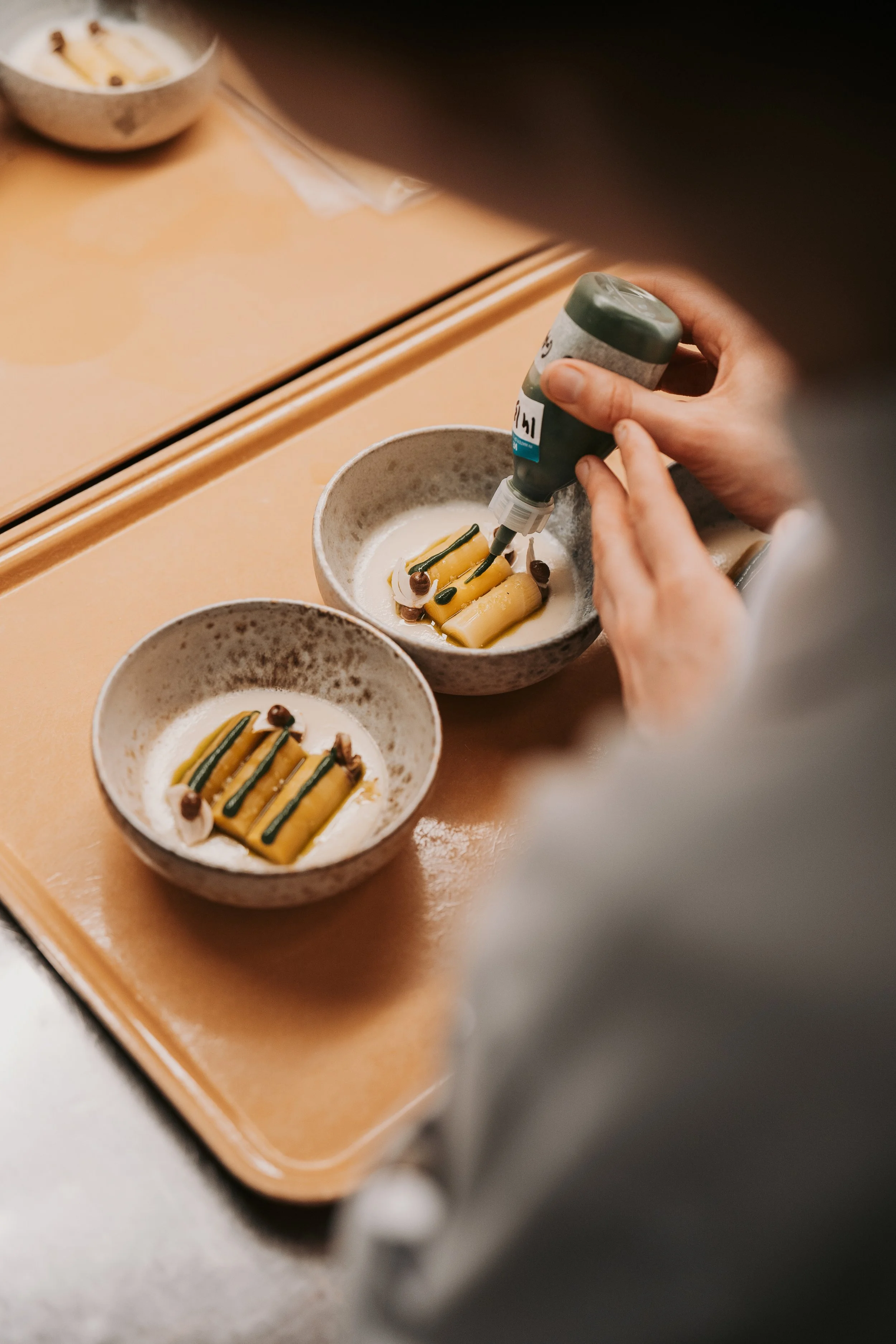 Culinary precision: Close-up of a chef’s skilled hands plating a fine-dining course with absolute precision.