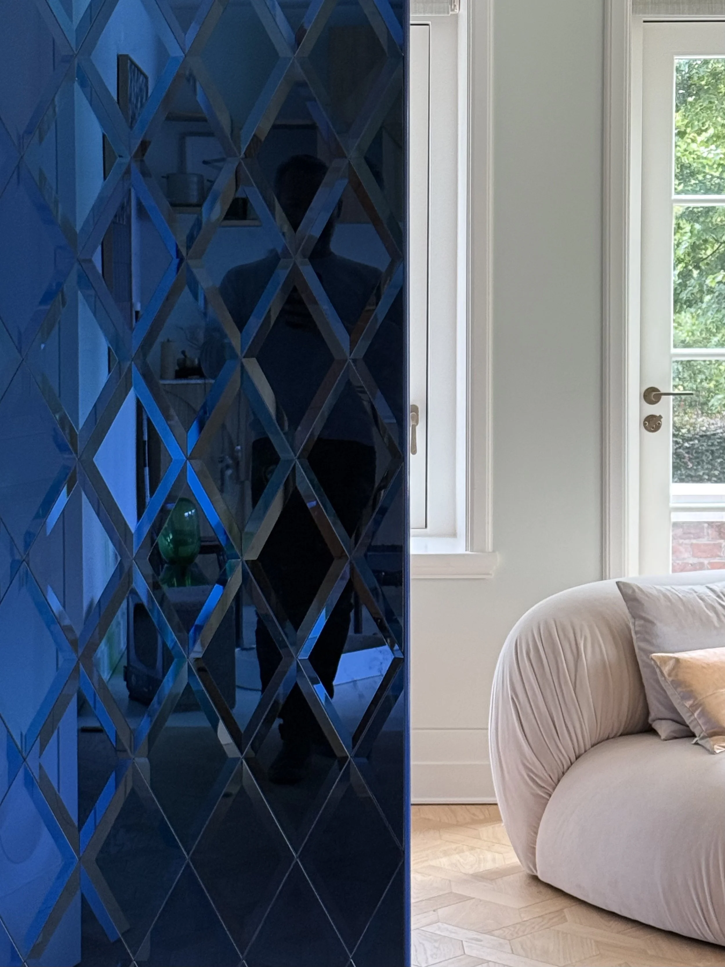 6. Atelier lounge corner: Glimpse of the custom blue textured triangular cabinetry paired with a soft, peach-beige Diesel Living armchair in the private studio space.